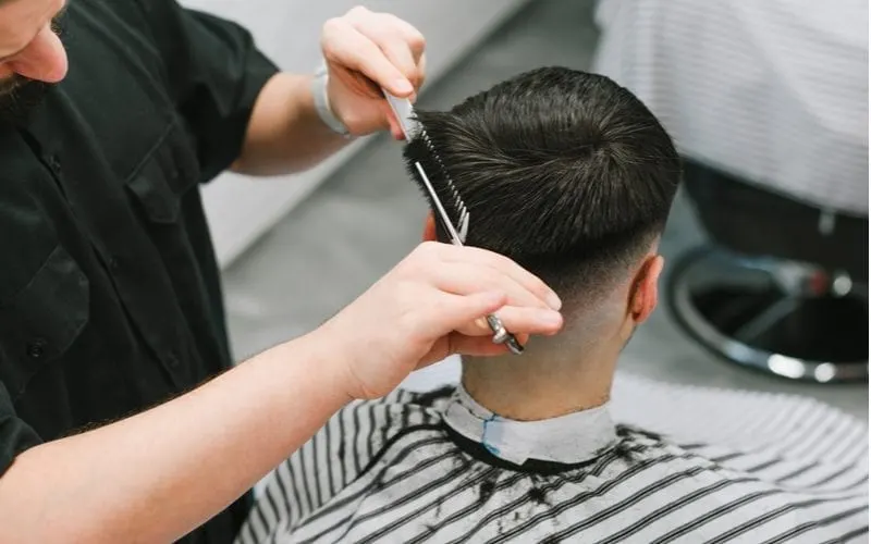 Closeup of a hairdresser cutting a bowl cut into the back of a man's head