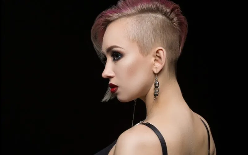 Beautiful young woman in a black bra and a shaved side of head in red lipstick and earrings