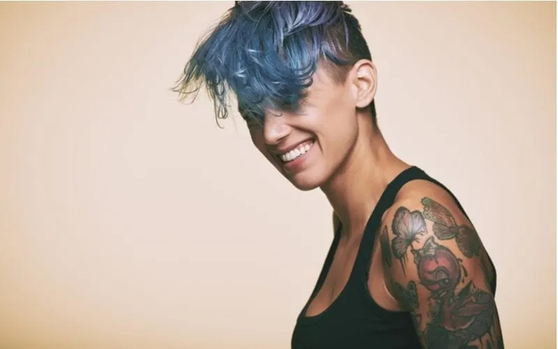 Woman with blue hair and a black tank top with a tattoo sleeve on her upper arm