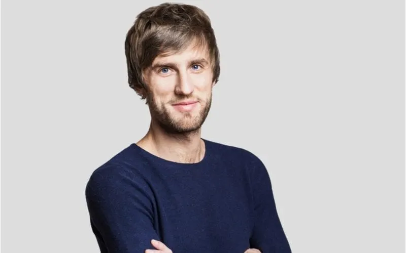 Handsome young smiling man wearing a dark blue shirt and crossing his arms