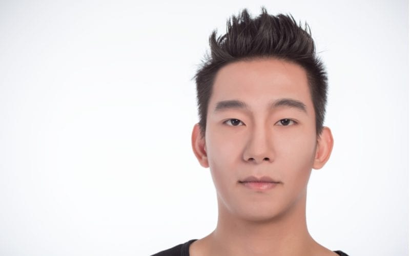 Young asian man with spikey hair looks straight at the camera in a studio