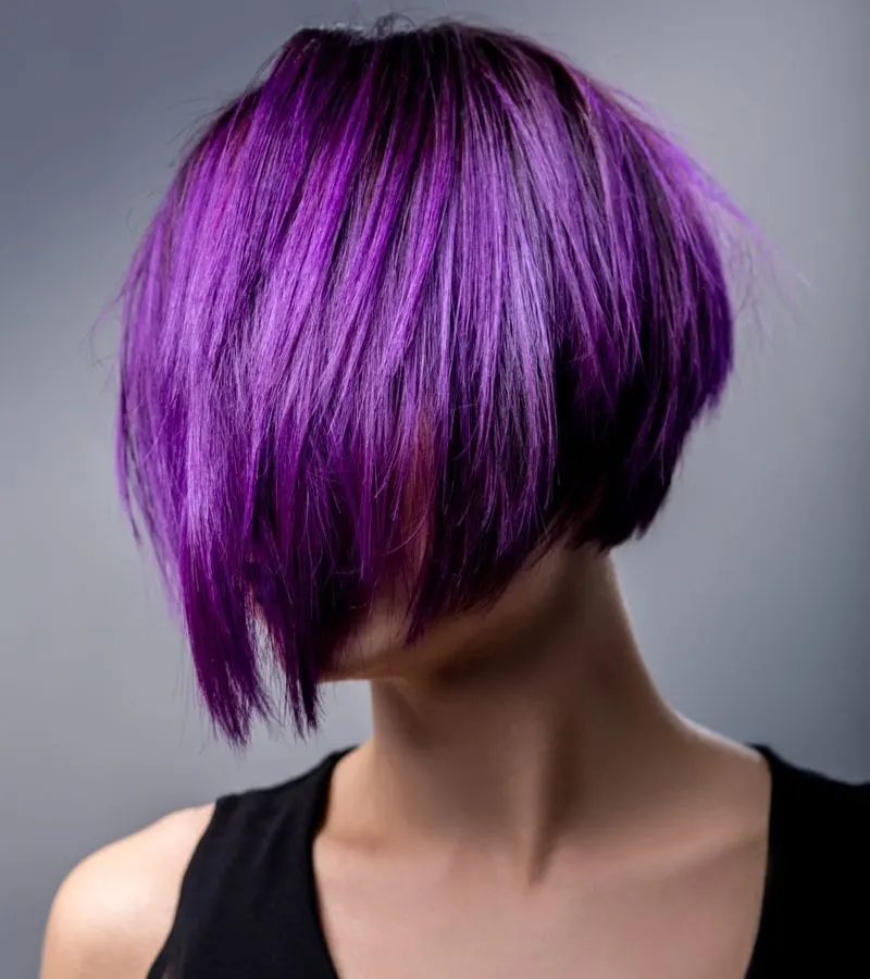Woman with purple hair cut into a bob cut that covers her face