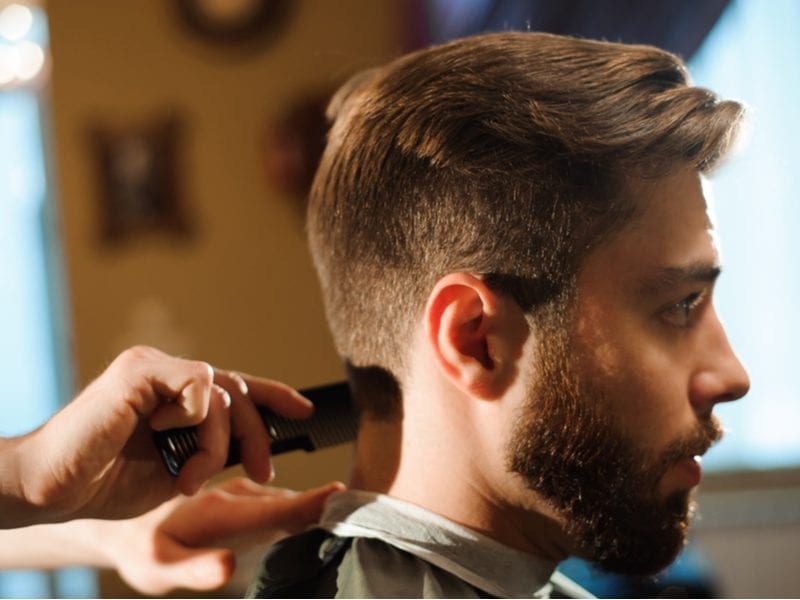 Man with a tapered fade gets a cut from a hairstylist