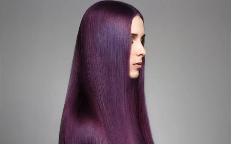 Purple eggplant hair on a woman with pale skin standing with straightened hair in a studio