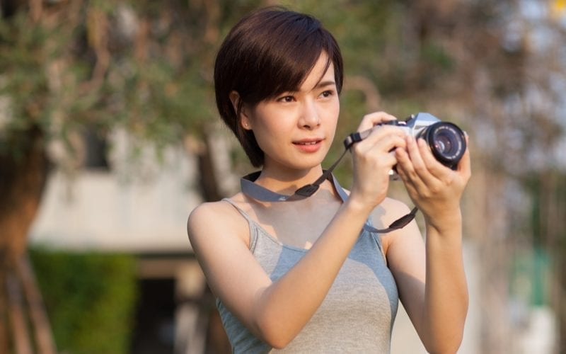 Short haired woman is asian and wears her camera around her neck