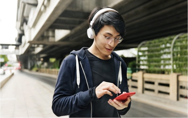 Classic long taper cut on an asian man walking under a bridge while wearing headphones