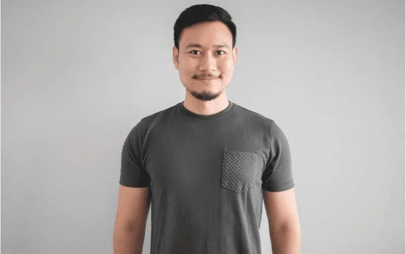 Asian man rocking a popular hairstyle and wearing a grey crew neck shirt with a pocket in the front
