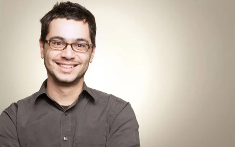 Man in glasses against a grey gradient background smiles