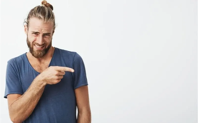 Guy with a man bun holds his finger up and points to his left