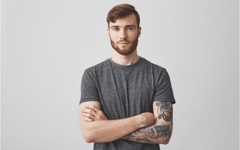 Man in a grey shirt in a studio wearing a haircut for men with widows peak