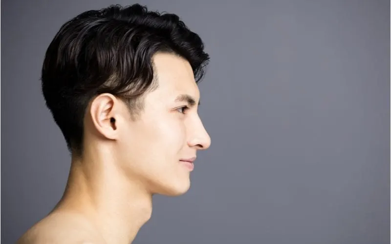 Side profile of an asian man looking straight ahead in a studio on a grey backdrop