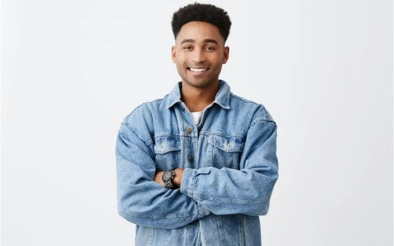 Man smiles while crossing his arms and wearing a high-top high fade haircut