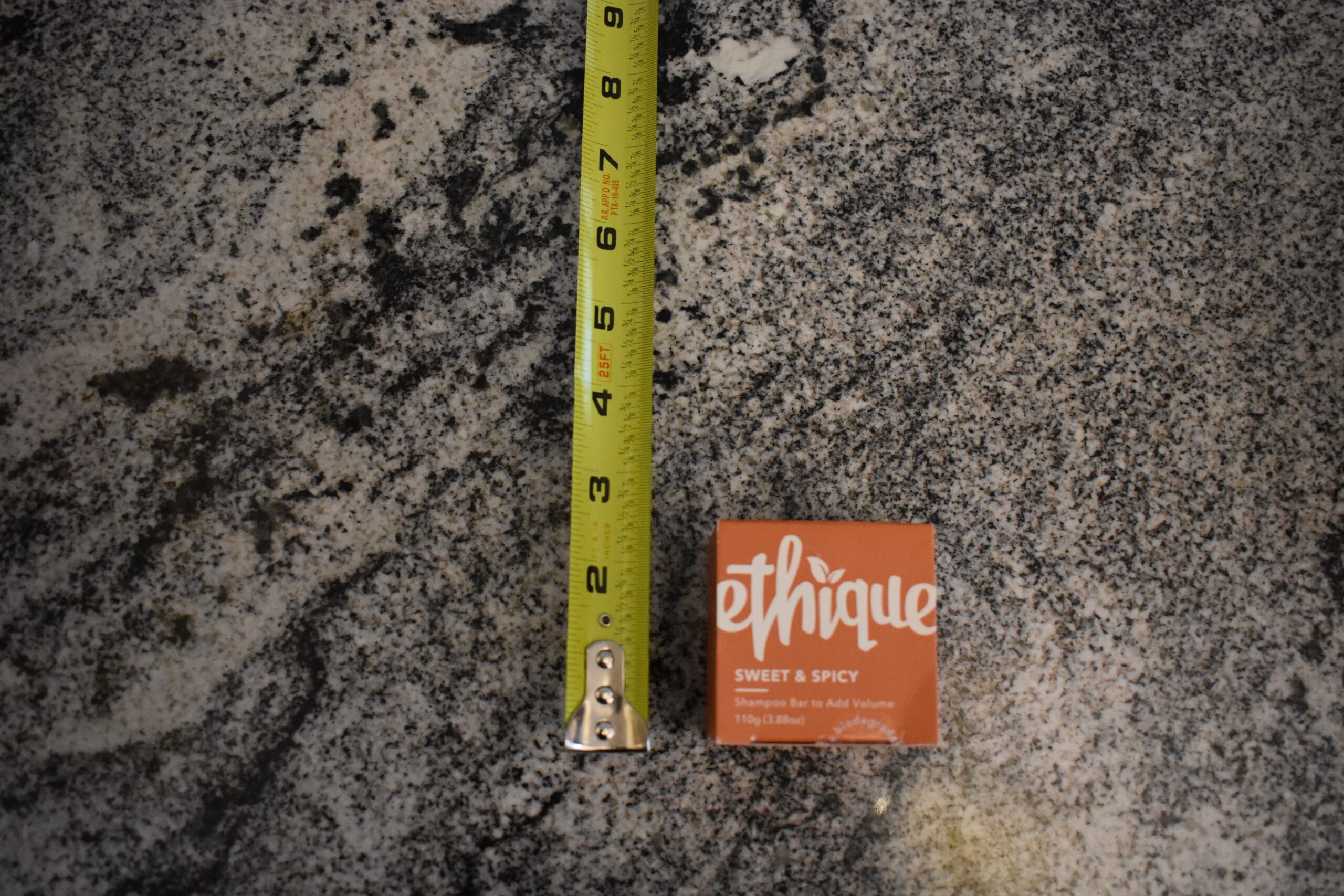 Ethique eco-friendly shampoo bar (one of our top shampoo picks) on the counter next to a tape measure