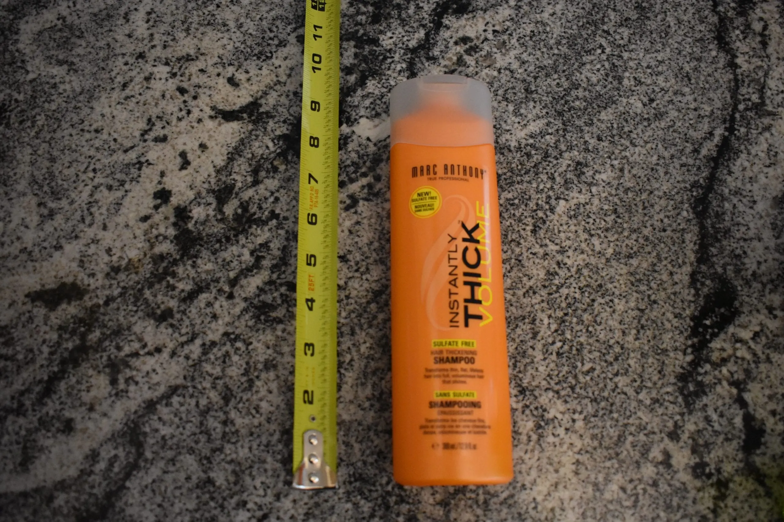 marc anthony thick hair shampoo next to a measuring tape on a granite counter