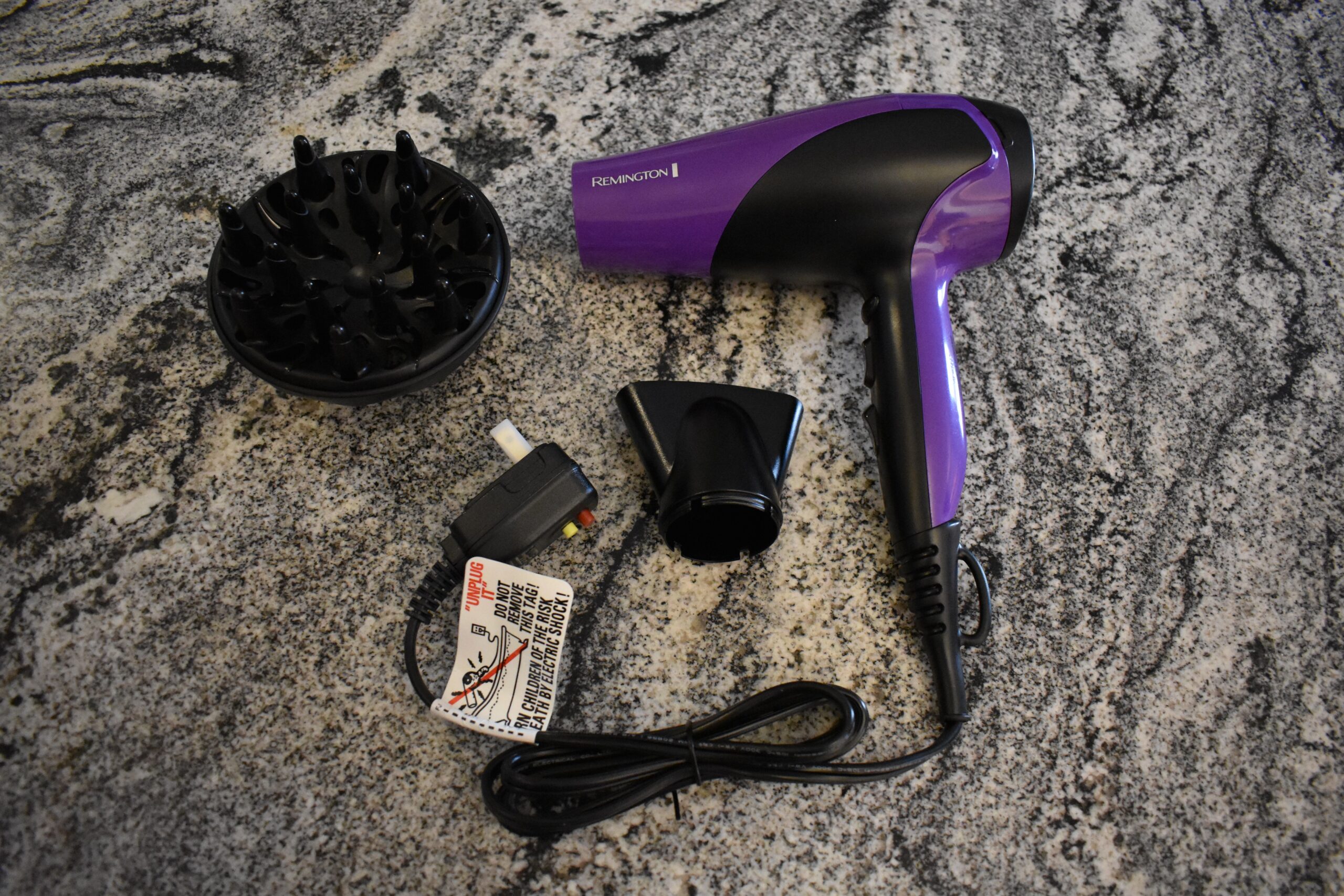 A pink Remington hair dryer sits on a grey granite counter