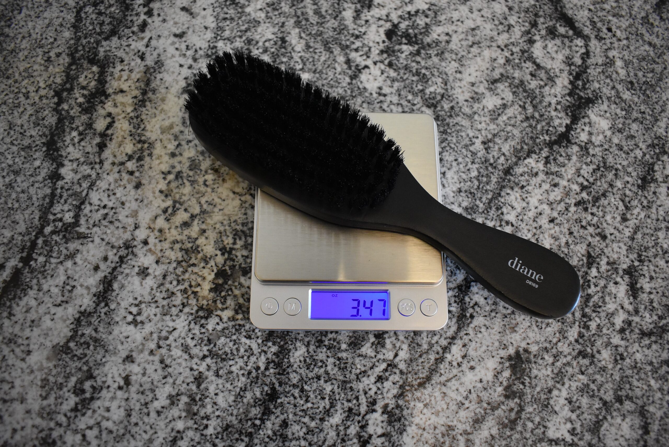 Close up of one of the best hair brushes, the Diane 100% Boar Bristle Brush, registering 3.47 oz on my scale