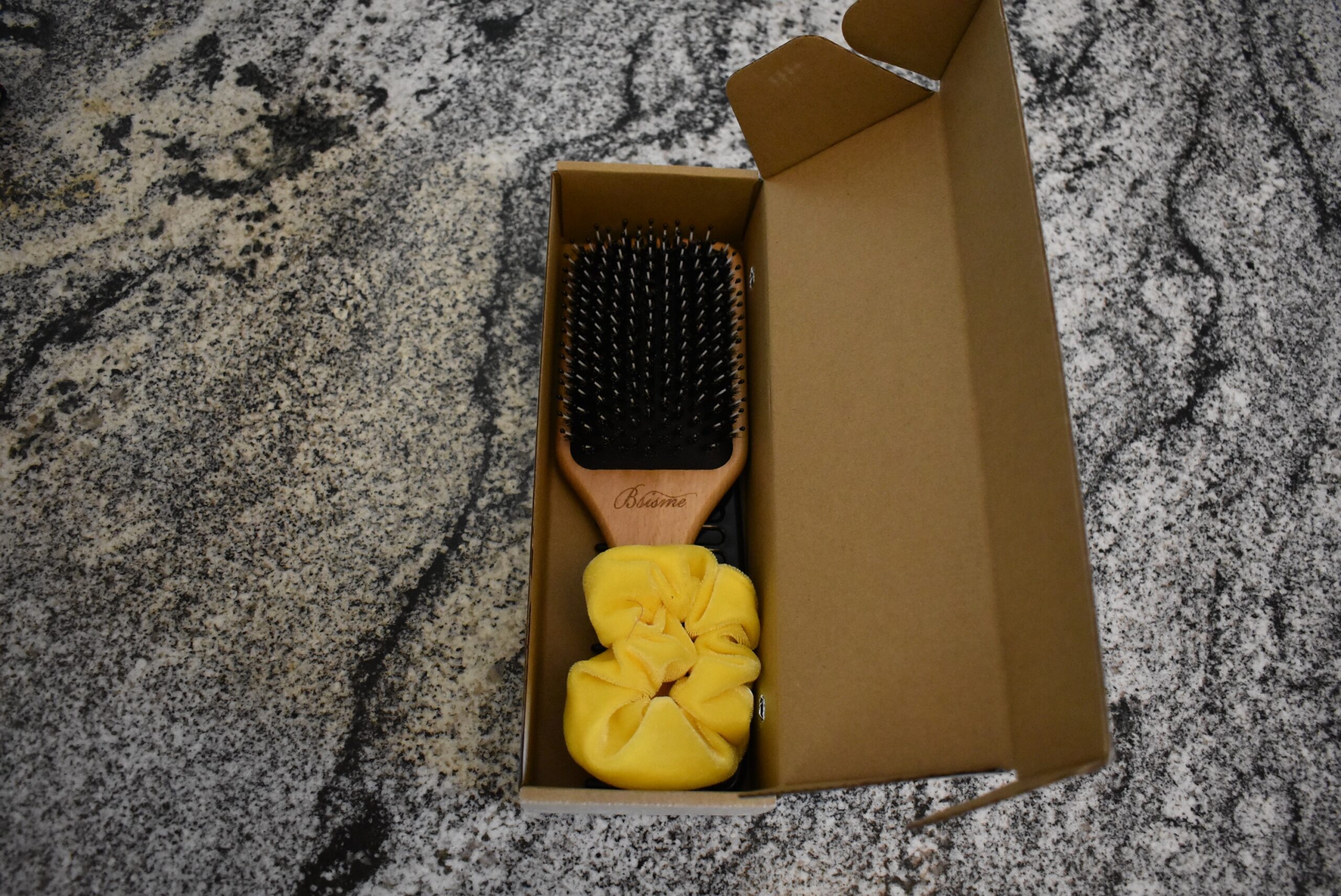 Open box of the bsisme boar head bristle brush with a scrunchie and comb