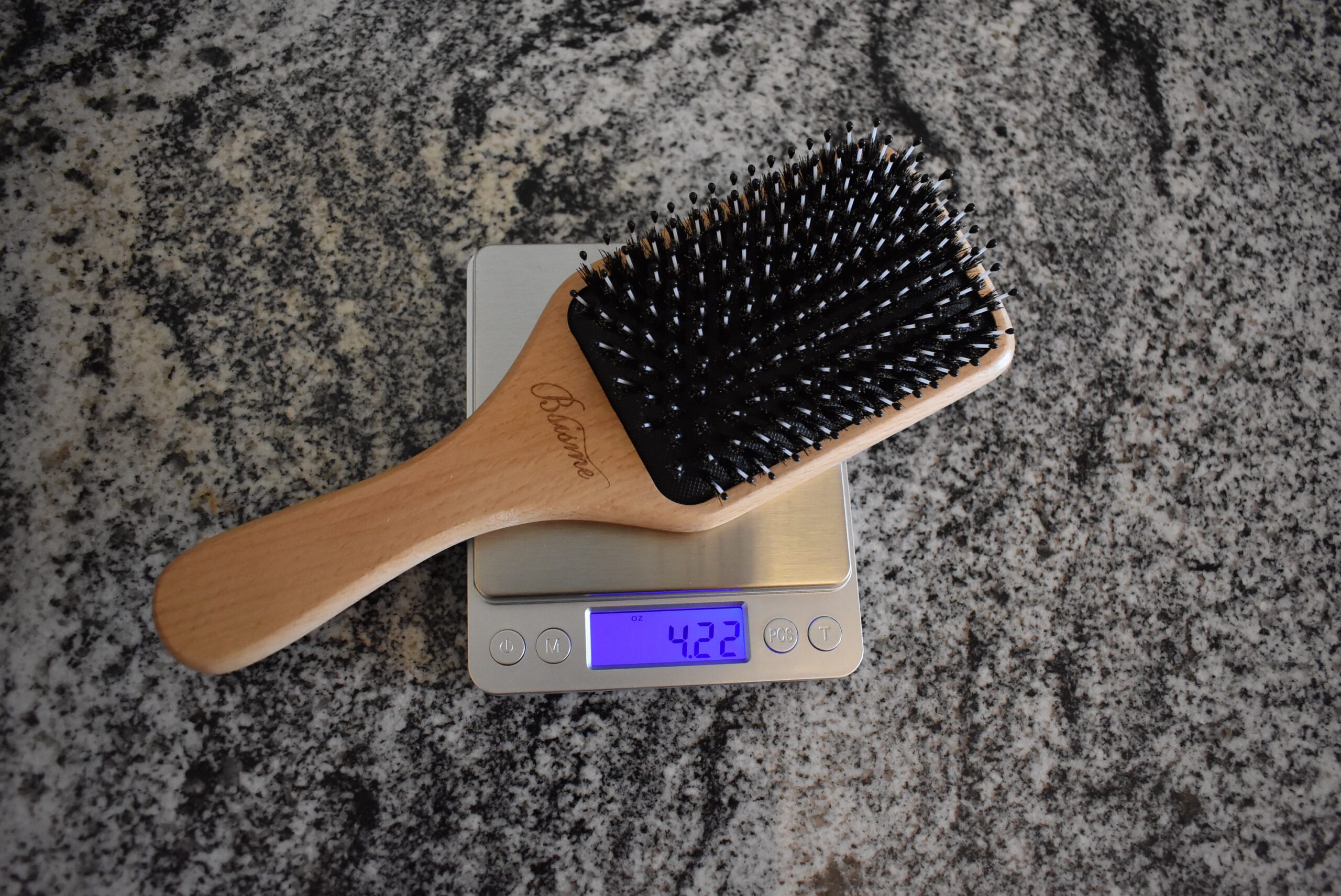 Bsisme Boar Bristle and Nylon Paddle Hairbrush on a scale, registering 4.22 oz