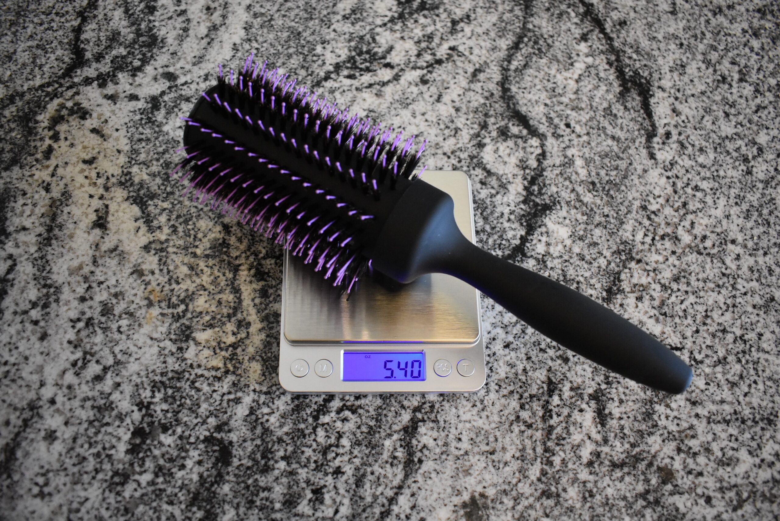 The Wet Brush Break-Free Volume & Body Round Brush on a scale, registering 5.4 oz