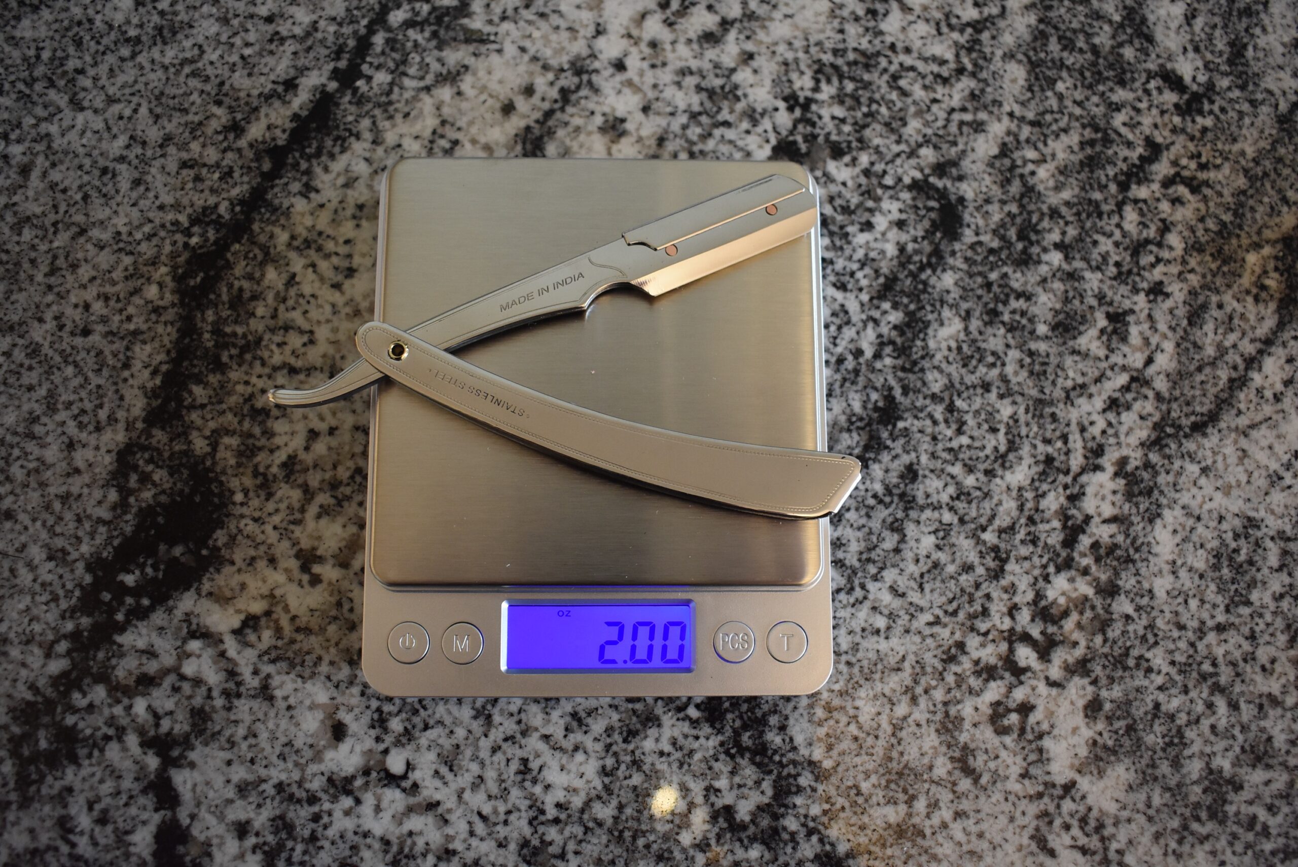 Parker straight razor slightly open and sitting on a scale registering 2.00 oz