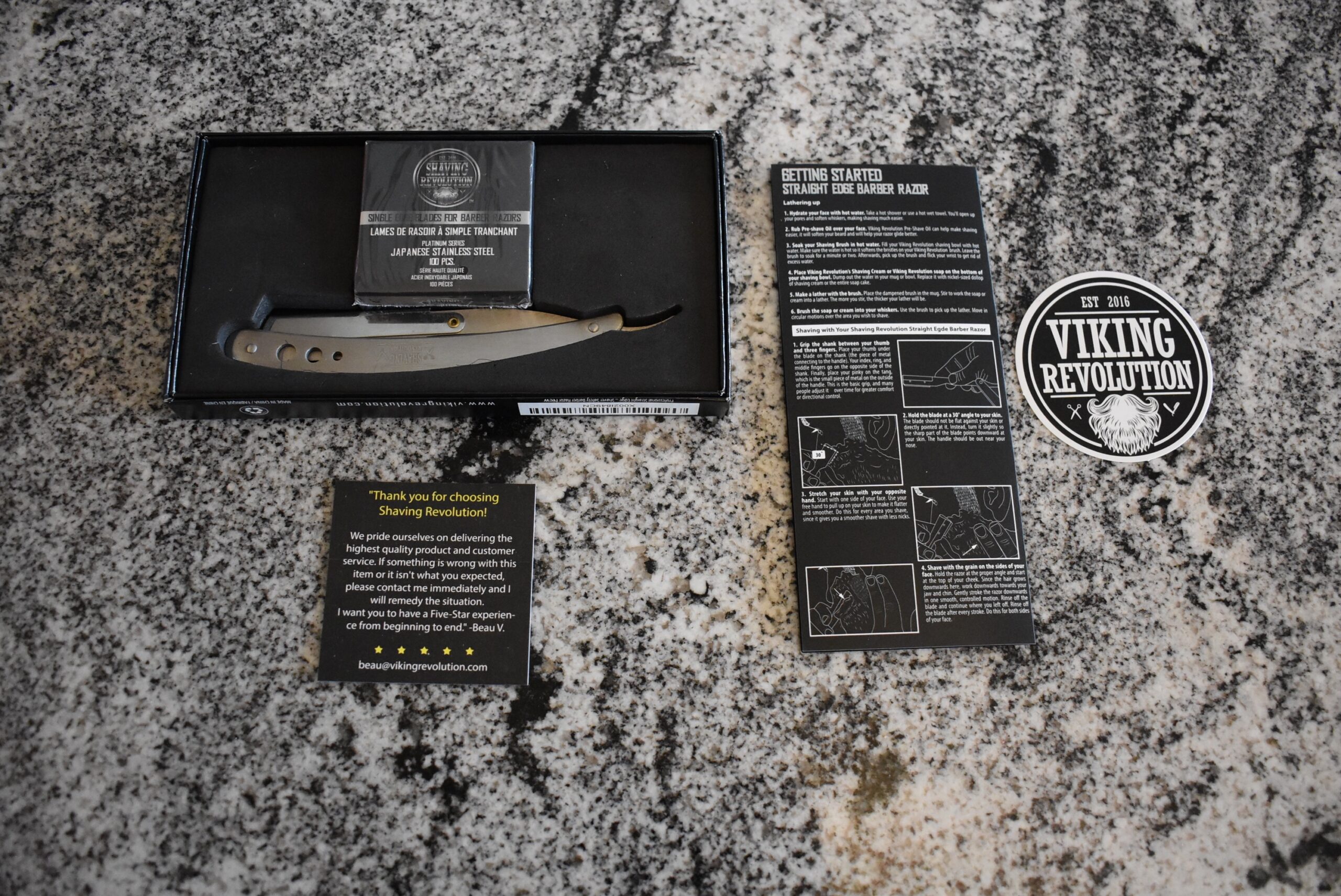 The Viking Revolution straight razor along with a number of inserts and blades on a granite counter