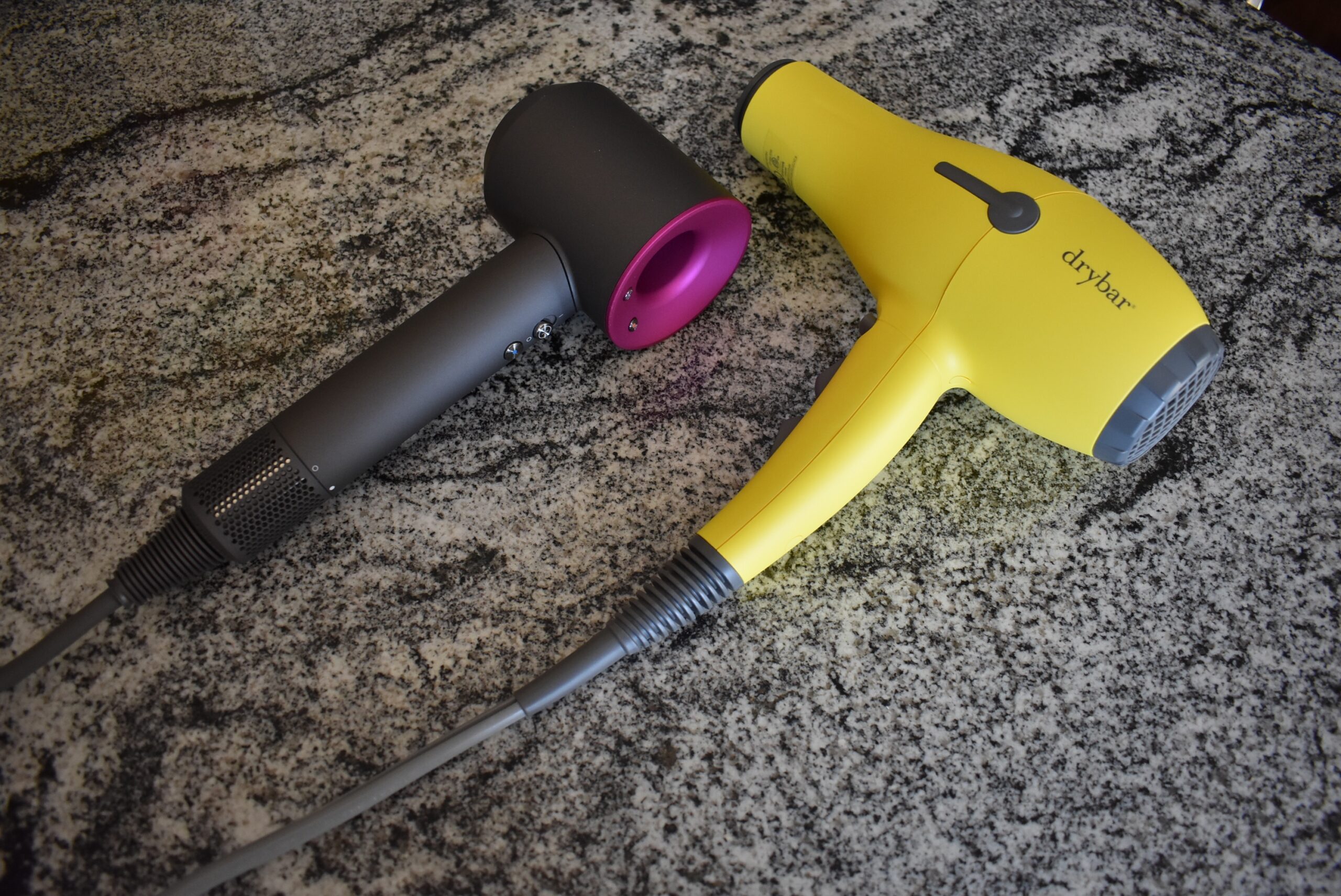 An angled view of the Dyson hair dryer for a product review next to the yellow drybar buttercup
