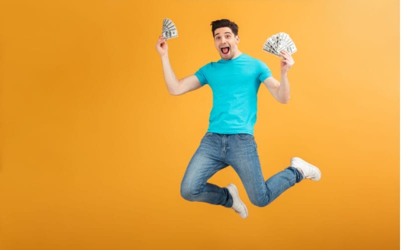 Guy jumping with joy and holding fanned money in his hand for a piece on Mastercuts prices