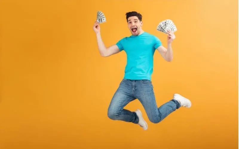 Guy jumping with joy and holding fanned money in his hand for a piece on Mastercuts prices