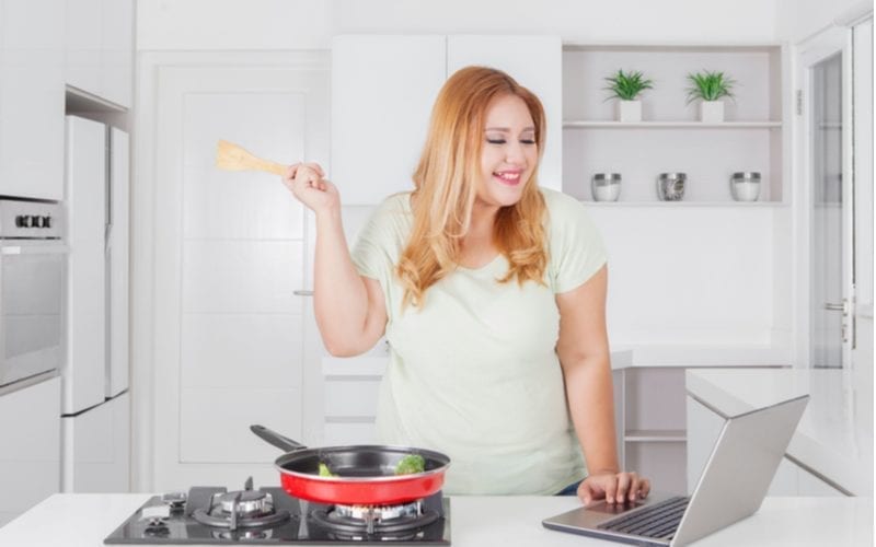 Picture of a happy woman cooking vegetables on a red pan in the kitchen