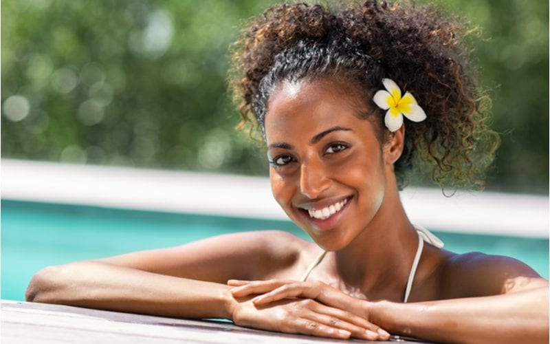 Woman with natural hair style (twin puffs) and a flower in her hair relaxing by the pool