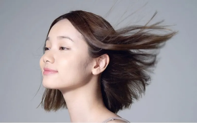 Lady with a long bob haircut that is au natural lets the hair blow in the wind away from her