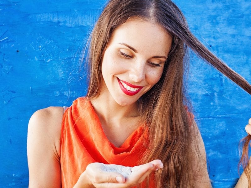 For a piece on how to use dry shampoo, a woman holding powder shampoo in her hand and a strand of her hair in another