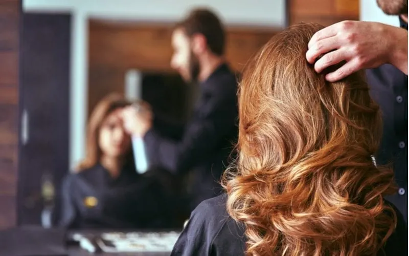 For a piece on Mastercuts Prices, a woman sits in a hair salon looking straight ahead