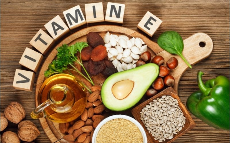 Lay-flat image of foods with vitamin e in them against a plain wood paneled background