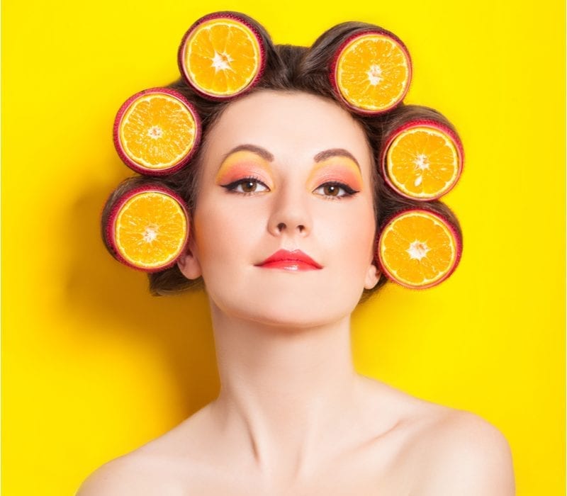 Woman with various supplements in her hair (oranges) for a piece on which vitamin is best for hair