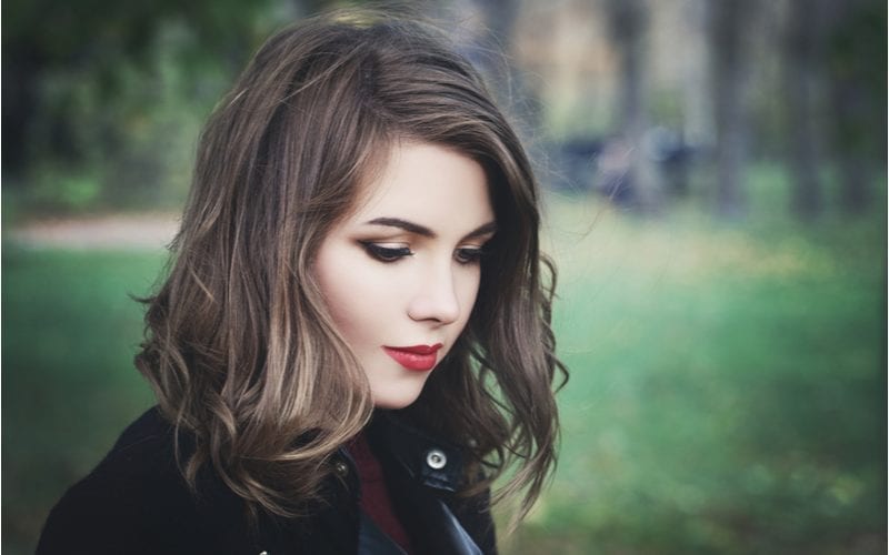 Woman with shoulder-length hair and fair skin wearing red lip and a peacoat while standing outside