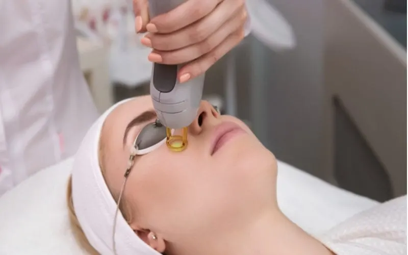 Woman getting a laser treatment on her face in a spa