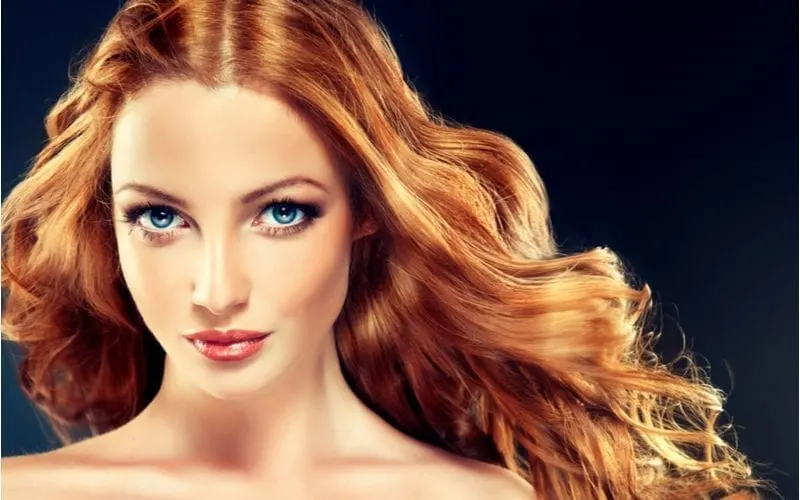 Beautiful model in a dark room and strawberry blonde hair gazes into the camera with her deep blue eyes