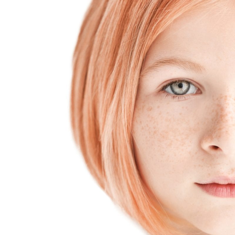 Woman with a long bob haircut looks directly at the camera and you can see her freckles