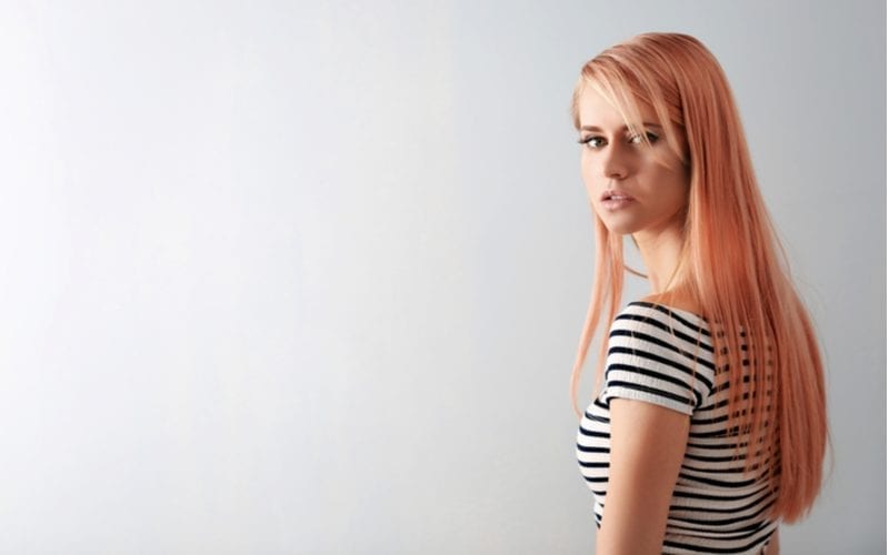 Younger gal in a striped white and black shirt and strawberry blonde hair looks over her left shoulder toward the camera