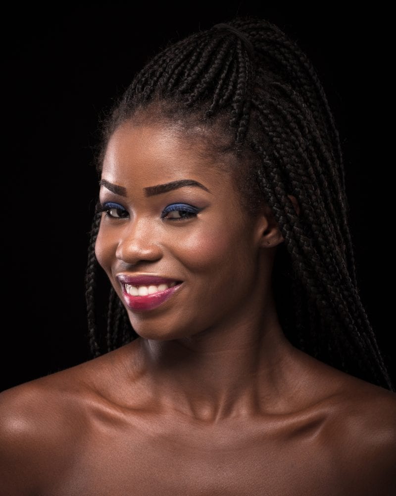 Smiling young woman wearing half-up braids in a dark room