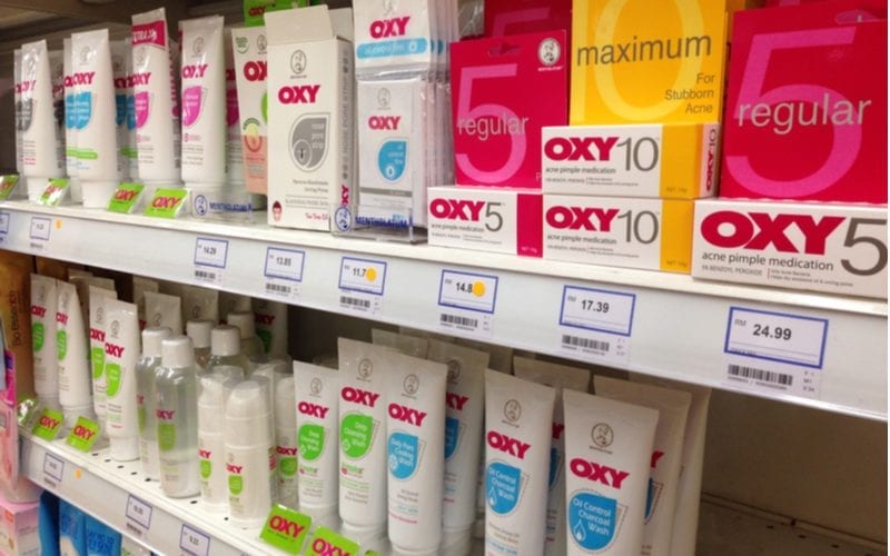 Lots of benzoyl peroxide treatments sitting on a shelf of a supermarket