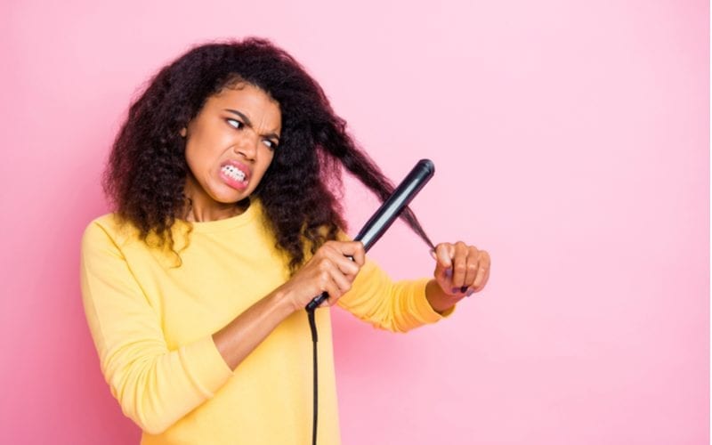Woman trying to straighten her thick hair for a piece on what hair types should avoid coconut oil