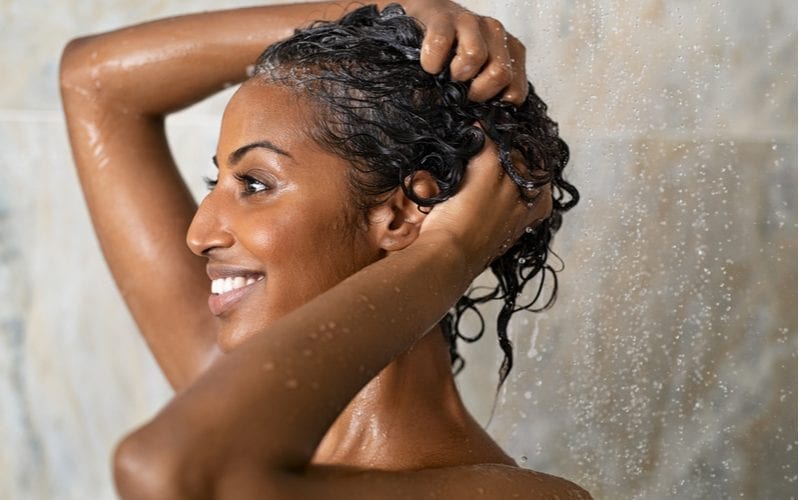 Pretty smiling Indian woman washing her hair in the shower before applying hair milk