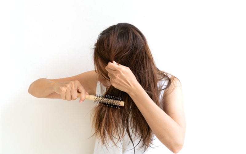 Asian woman brushing her hair in preparation for a blowout