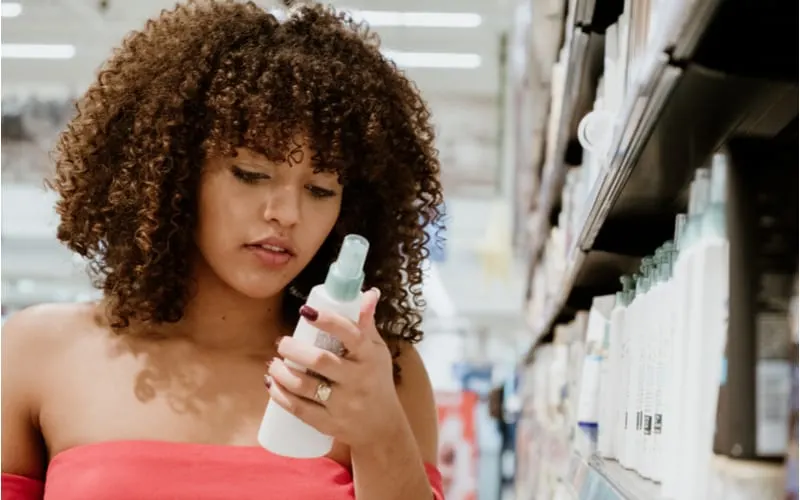 As an image for a piece on choosing the right hair milk, a young woman with curly hair looking at the best hair milk in a store
