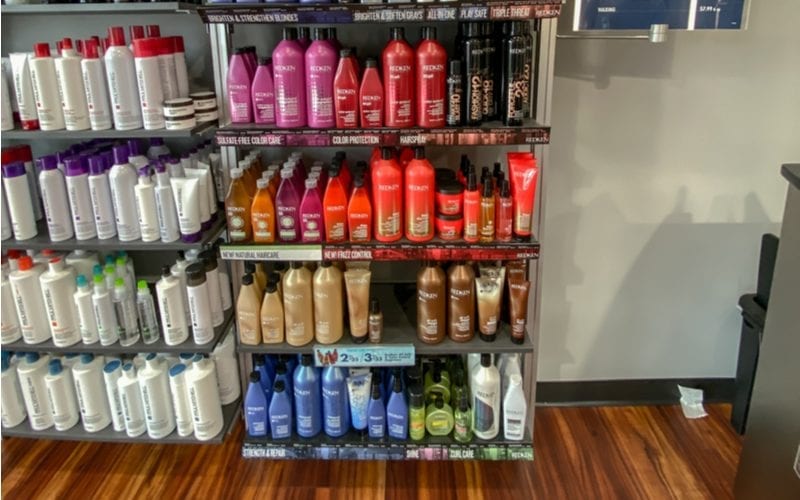 Een hoop flessen Redken Shampoo op een plank van een Supercuts