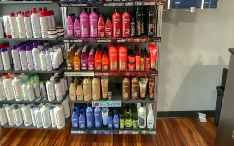 A bunch of bottles of Redken Shampoo sitting on a shelf of a Supercuts