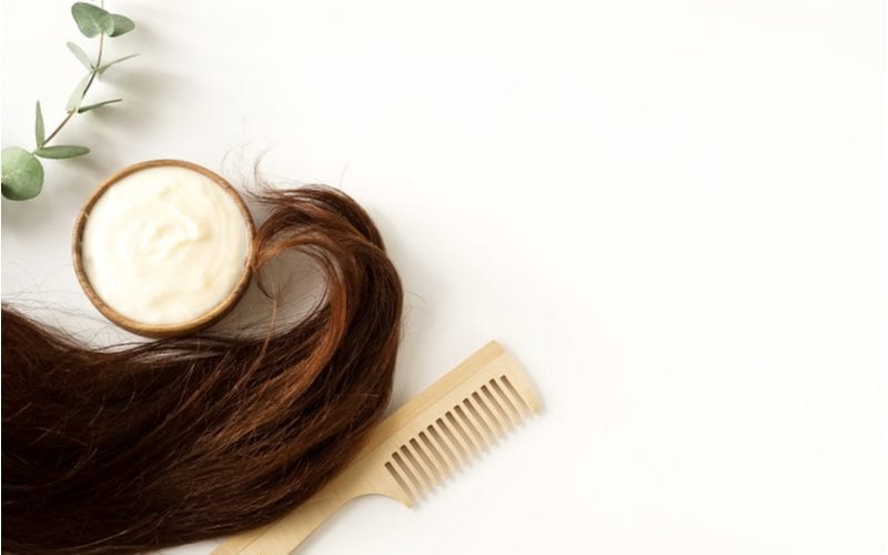 For a piece on what is a hair mask, brunette long hair sits next to a comb and a mask with a leaf