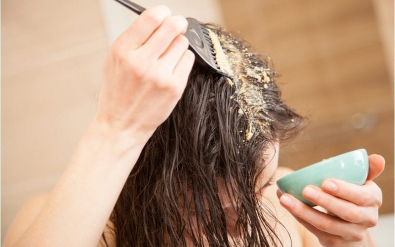 Woman applying a hair mask to the roots of her hair for a post on what is a hair mask